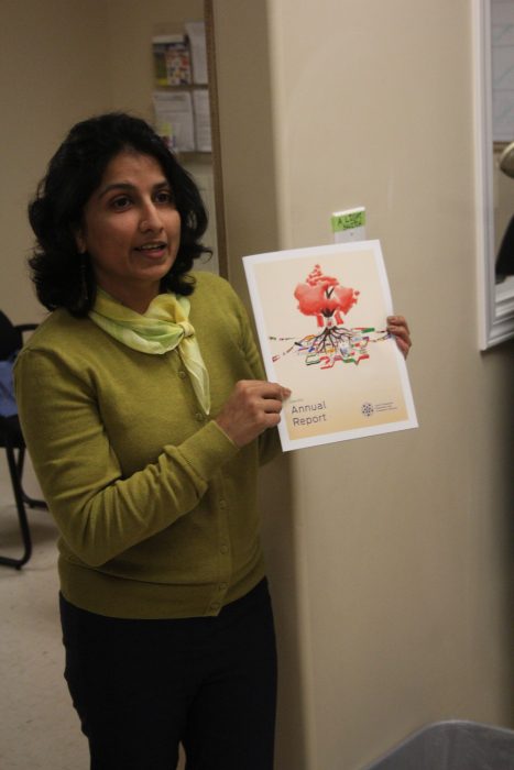 Tahira Saeed, Program Manager at SOICS, shows off the Annual Report and creative design on the front cover.